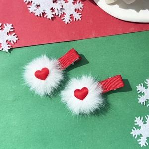 Detail van zoete hart pompon haarclips met zacht wit bont en rode hart accenten