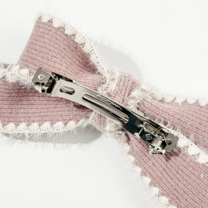 Detail view of the pink knitted bow clip with white fuzzy edges and metal spring fastener