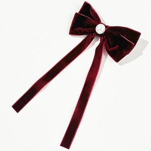 Macro detail of wine red velvet bow hair clip with an elegant white pearl center