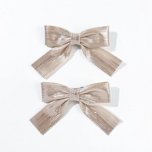 Close-up of champagne gold glitter bow hair clips with textured metallic fabric finish