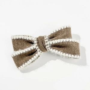 Detailed texture of brown knitted bow hair clip with white faux fur trim for winter