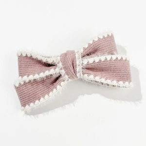 Detailed shot of pink knitted bow hair clip with white plush trim and ribbed texture