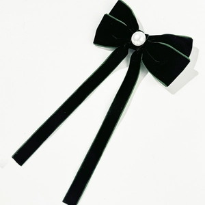 Detail of dark green velvet bow hair clip with large pearl and long streamers