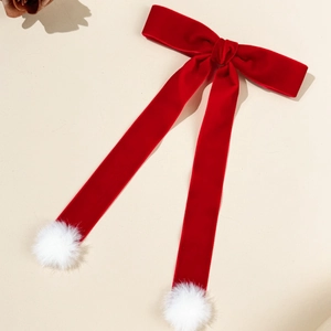 Détail d'un nœud en velours rouge avec de longues lanières et des pompons blancs