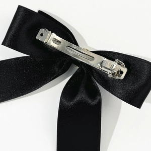 Détail du nœud en satin noir montrant la barrette en métal argenté avec gravure Paris