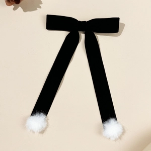Détail d'un nœud papillon élégant en velours noir avec rubans et pompons blancs soyeux
