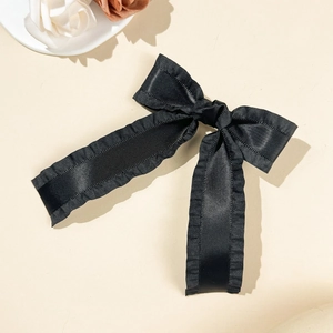 Gros plan d'une barrette noeud en satin noir avec bords froissés sur fond floral élégant