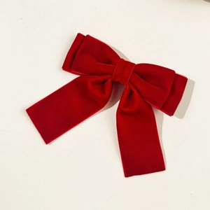 Macro view of a red velvet bow hair clip showing soft fabric texture and deep red color
