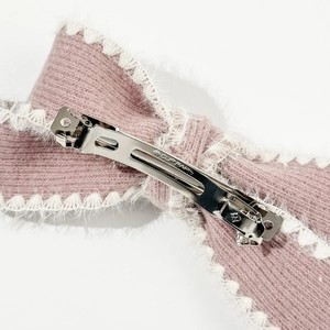 Pink knitted bow hair clip with white plush trim and silver metal spring fastener