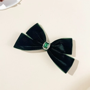 Elegant dark green velvet bow hair clip with an emerald-colored gemstone and rhinestones