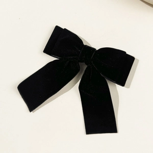 Detailed macro view of the double-layered black velvet bow hairpin with long ribbon tails