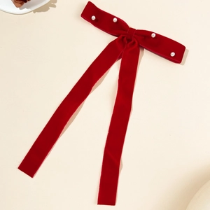 Detail of red velvet bow hair clip with faux pearl embellishments and elegant ribbons