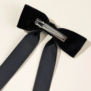 Dettaglio del retro di un fiocco in velluto nero con una robusta clip a becco d'anatra