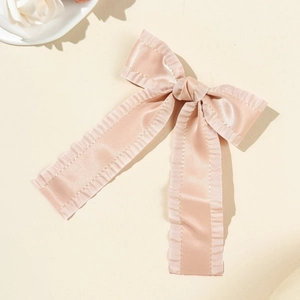 Gros plan d'une barrette à cheveux en satin rose avec bords froissés et longs rubans