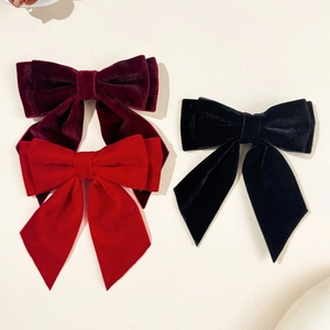 Detail view of large velvet bow hair clips in wine red, bright red, and classic black