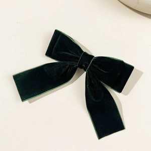 Detail of dark green velvet bow hair clip with long ribbons and elegant texture