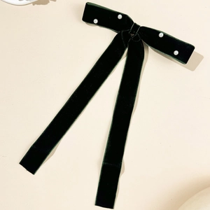 Detail of dark green velvet bow hair clip with white pearls and long ribbon streamers