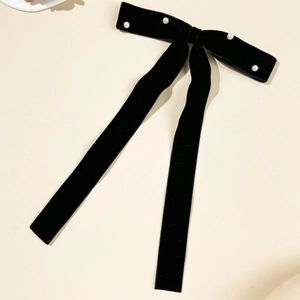 Detail of elegant black velvet bow hair clip with white faux pearls and long ribbons