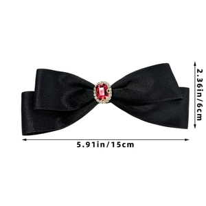 Detail of elegant black satin bow hair clip with red gemstone and sparkling rhinestones
