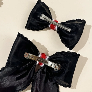 Detail of black mesh hair clips with red velvet center and silver metal spring fasteners