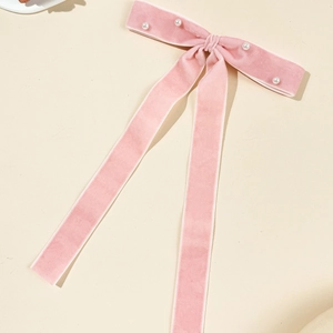 Close-up of pink velvet bow hair clip with white pearls and elegant long ribbons