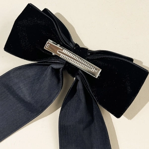 Detail view of black velvet bow hair clip showing the silver metal alligator clip mechanism
