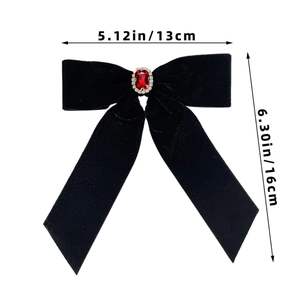 Detail of black velvet bow hair clip with red rectangular gemstone and silk streamers