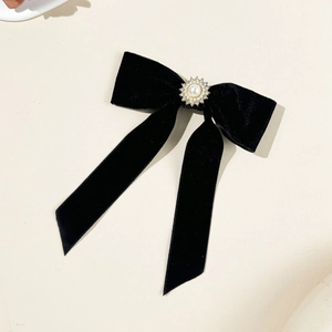 Dettaglio di un elegante fiocco in velluto nero con perla e strass girasole sulla clip