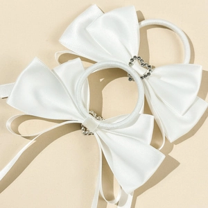 Detail of white satin bow hair ties with sparkling silver heart rhinestones and elastic bands