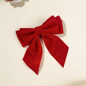 Detail showing the fine velvet texture and double-layered red bow hair clip design
