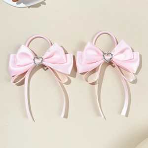 Close-up of pink satin bow hair ties featuring heart-shaped rhinestone center buckles