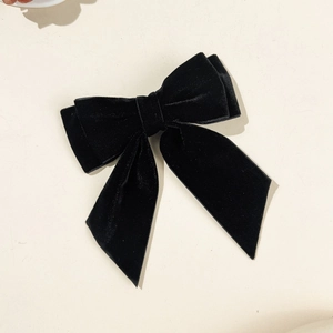 Detail of elegant black velvet bow hair clip with double-layer design and long ribbons