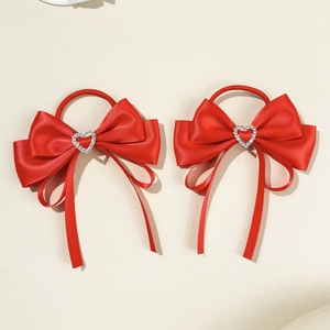 Detail view of red satin bow hair ties with sparkling heart-shaped rhinestone centers