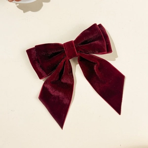 Detailed view of the layered dark red velvet fabric texture on the elegant bow hair clip