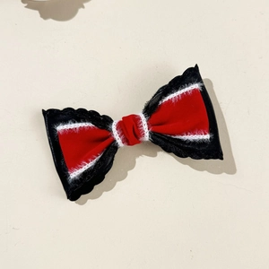 Detail of red and black velvet bow hair clip with white plush trim and wavy edges