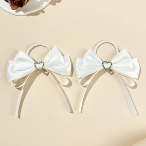 Close-up of white satin bow hair ties with sparkling heart-shaped rhinestone details