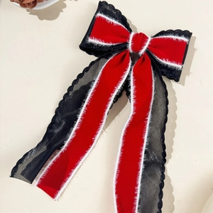 Macro shot of large red velvet bow hair clip with black lace mesh and long streamers