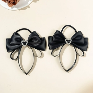 Close-up of black satin bow hair ties with sparkling silver rhinestone hearts and long ribbons
