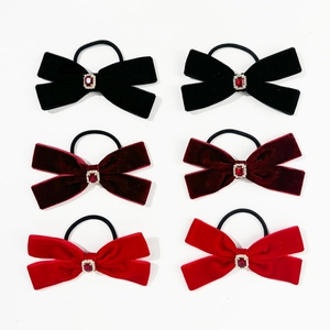 Close-up of velvet bow hair ties featuring ruby-style gems and sparkling rhinestones