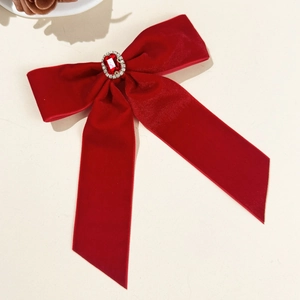 Detail of red velvet bow hair clip with central ruby gemstone and sparkling rhinestones