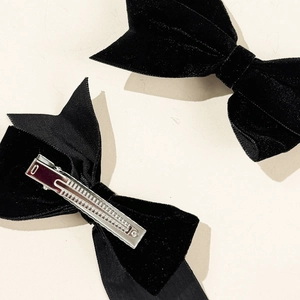 Detailed close-up of black velvet bow hair clips showing front fabric and metal alligator clip