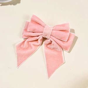 Détail d'une pince à cheveux nœud en velours rose clair avec des rubans élégants