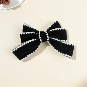 Vue détaillée d'une pince à cheveux nœud noir avec d'élégantes bordures en dentelle blanche