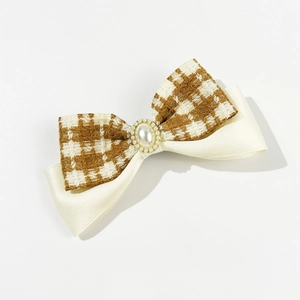 Detail of tweed checkered bow hair clip with ivory pearl accent and satin ribbon