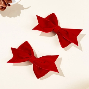 Detail of two red velvet bow hair clips with soft texture and classic design