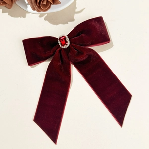 Detailed macro of vintage burgundy velvet bow hair clip with luxury red gemstone centerpiece