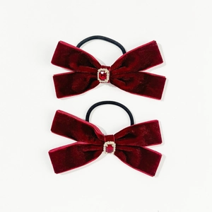 Elegant pair of wine red velvet bow hair ties with ruby rhinestone center on white background