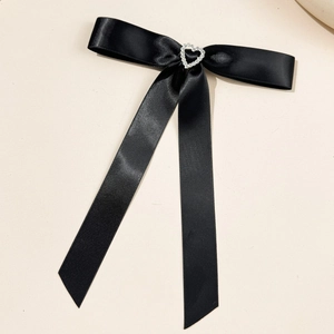 Dettaglio di un fiocco in raso nero con decorazione centrale a forma di cuore in strass