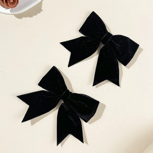 Detailed macro view showing the soft texture of two elegant black velvet bow hair clips