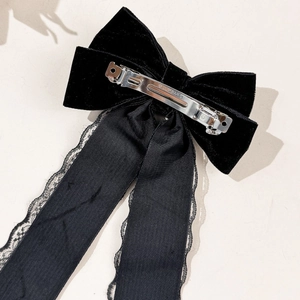 Detail of vintage velvet bow hair clip showing lace ribbon edges and metal spring clip